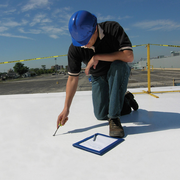 Roofing inspector evaluating a commercial flat roof